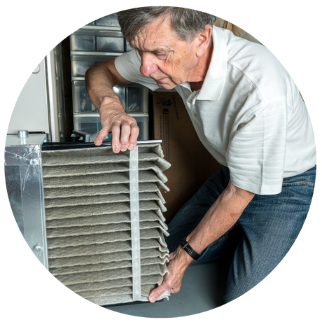 A man doing home maintenance by changing a filter on a furnace.