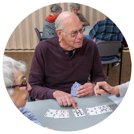 Elderly man pointing to a card while playing card games with others at the Golden Circle.