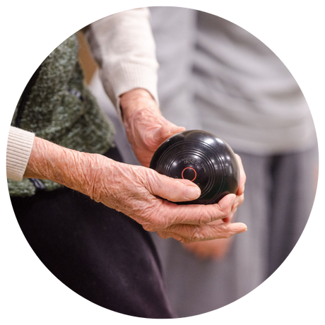 Elderly woman's hands holding a bocci ball.